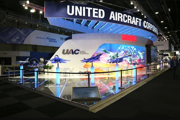 United Aircraft Corporation (UAC) exhibition booth at an international airshow, featuring scale models of aircraft, illuminated displays, and branding showcasing Russia’s aviation projects.