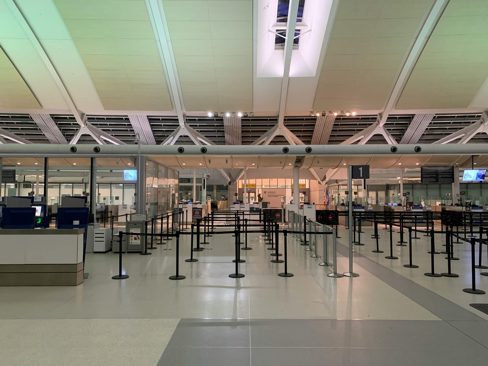 Wide shot of an airport check-in area with multiple counters and barrier ropes, completely empty of passengers and staff, emphasizing the vacant and quiet atmosphere in an otherwise operational space