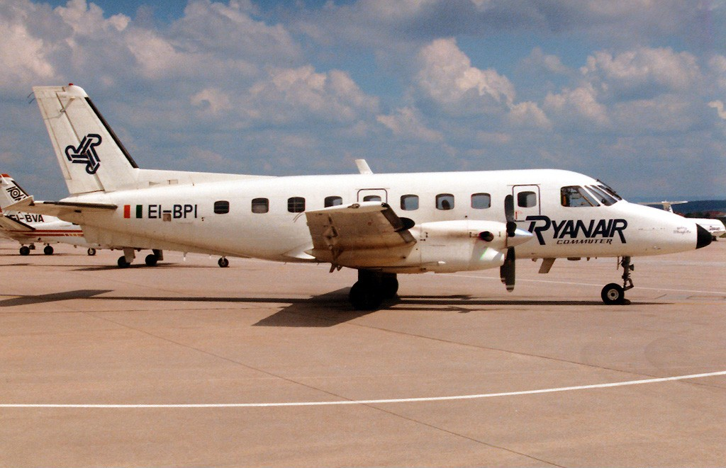 A Ryanair commuter aircraft is parked on the tarmac under a partly cloudy sky.